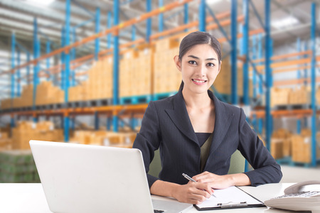 Business woman using laptop with smiling at warehouse. People working concept.の写真素材