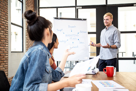 Businessman present marketing plan to team with attractive smile. People working at office place together.の写真素材