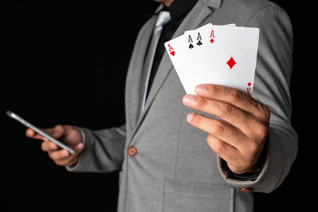 Businessman holding ace card and smartphone isolated on blackの写真素材