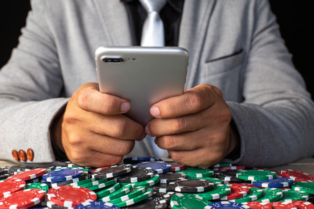 Man holding smartphone  isolated on black background. Casino and Broker concept.の写真素材