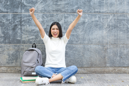 Young asian woman with success felling on cement background. Woman with education concept.の写真素材