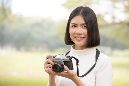 Attractive Asian shot hair woman holding retro camera with smiling, Woman using camera at outdoor place.の写真素材