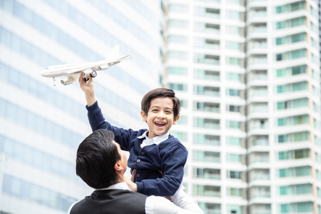 Portrait of Boy carrying airplane with attractive smile. Father holding son with happy emotion at city background.の写真素材