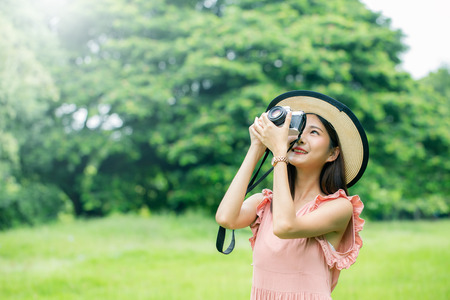Beautiful woman using camera to taking photo at the public garden. Women resting at garden in holiday. People with lifestyle, relax, holiday concept.の写真素材