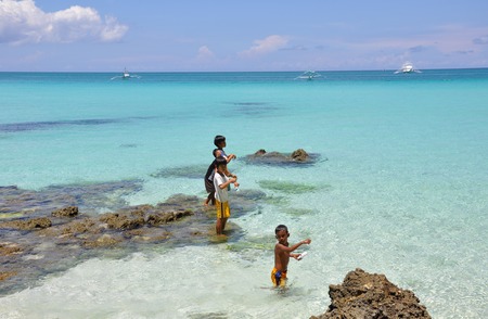 Boracay island, Philippines - August 12, 2011: three little boys are fishing  on Boracay beach in Philippinesのeditorial素材