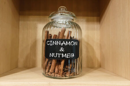 cinnamon and nutmeg in jar on shelvesの写真素材