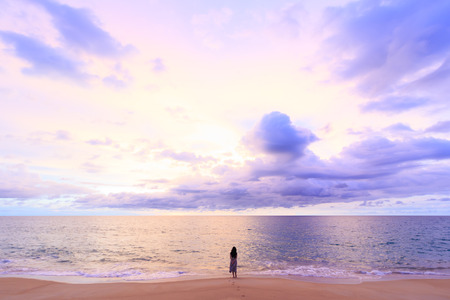 one women standing on soft cloud and sunset background with a pastel color blue to orange gradient.Blurred sea effect over the ocean. pastel colors.の写真素材
