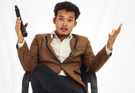 Businessman bodyguard on brown suit holding the gun sitting on the chairの写真素材