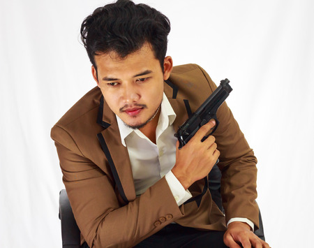Businessman bodyguard on brown suit holding the gun sitting on the chairの写真素材
