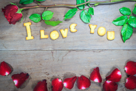 Happy Valentine\'s Day red roses on dark recycled wood background with word I Love You dessertの写真素材