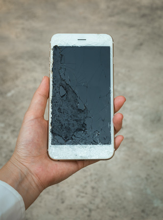 Closeup of Crack Display Smartphone Screen Holding on Hand with Blurry Backgroundの写真素材