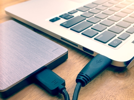 External or portable hard drive (HDD) connected to laptop computer for transfer or backup data on...