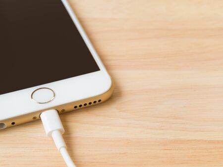 CHIANGRAI, THAILAND -JULY 28, 2016: Closeup image of the Apple iPhone 6 charging with Lightning USB Cable on the wooden table on July 28, 2016 in Chiangrai Thailand.のeditorial素材