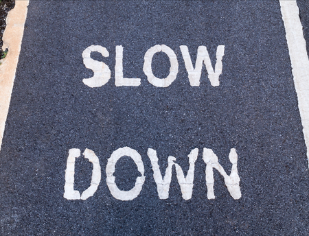 Close up of 'SLOW DOWN' sign marking on bike lane, for warning the drivers and cyclist to reduce speed.の写真素材