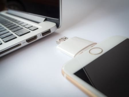 CHINGRAI, THAILAND -SEPTEMBER 7, 2016: Close-up image of two way external flash storage transfering data with Apple iPhone 6 and close to Apple Macbook Pro Retina on white background. Focus with USB connector.のeditorial素材