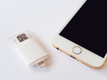 CHINGRAI, THAILAND -SEPTEMBER 7, 2016: Close-up image of two way external flash storage (Lightning and USB) and Apple iPhone 6 isolate on white background.のeditorial素材