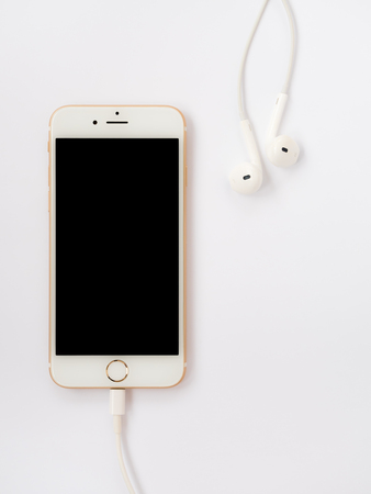 CHIANGRAI, THAILAND -SEPTEMBER 9, 2016: Close-up image of new Apple iPhone 7 mockup connect with charging cable (Lightning) and Apple EarPods on white background with copy space.のeditorial素材