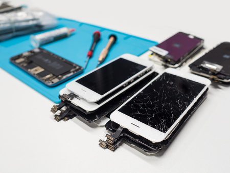 Close-up image of group of cracked smartphone screen prepairing for repair on white table