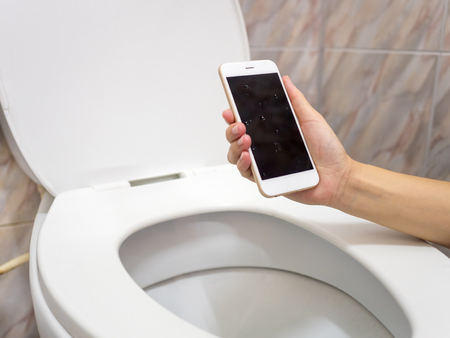Human hand holding wet smart phone in water closet. Water damage, waterproof concept.
の写真素材
