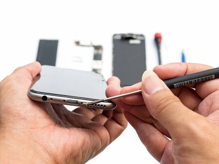 Close-up of technician being unlock screw with screwdriver on blurred smartphone component...