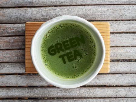 Top view of organic green tea matcha with text "GREEN TEA" in foam in white japanese style ceramic bowl after ceremony processingの写真素材