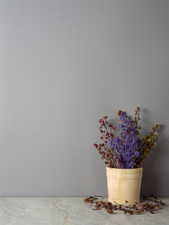 Group of bouquet dried and wilted multiple color Gypsophila flowers in wood bucket on matt marble floor and gray backgroundの写真素材