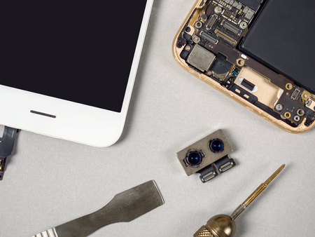 Smartphone dual camera rounded by smartphone components and tools on technician or engineer desk