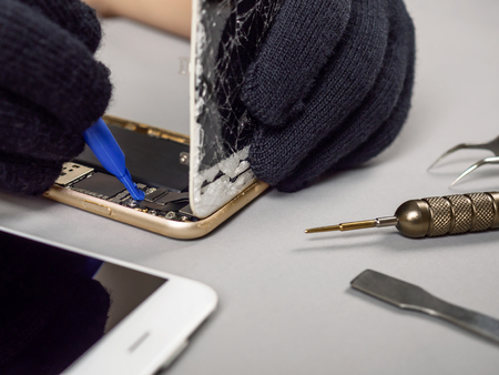 Technician or engineer disassembling components broken smartphone for repair or replace new smartphone battery on deskのeditorial素材