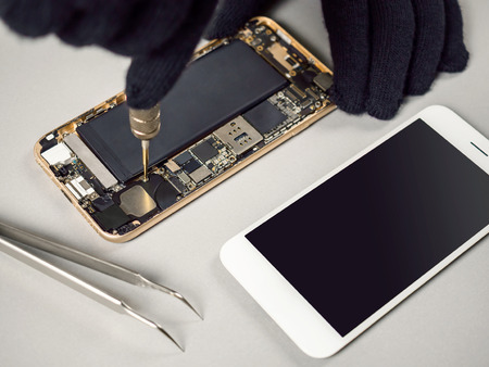 Technician or engineer disassembling components broken smartphone for repair or replace new part on deskのeditorial素材