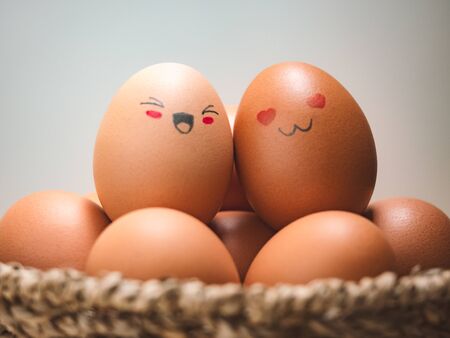 Egg lovers have happy faces of men and women on the pile of eggs in the basket. Organic egg food ingredients, Couples, Easter, Valentine's day concept.の写真素材