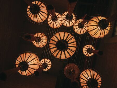 Low-angle under group of ancient Chinese lanterns with warm light hanging in darkness. Interior design conceptの写真素材