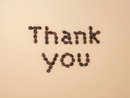 Roasted coffee beans arranged in letters on light brown background for coffee menus or coffee shop signsの写真素材