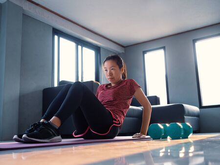 Good shape, strong and fit women in sportswear doing workout at home. Health care, people exercise and domestic living concept.の写真素材