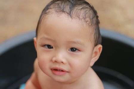 Close-up of Asian adorable wet toddler kid playing in outdoors. Baby care and childhood concept.の写真素材