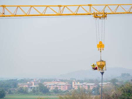 Construction workers were hung with cranes to control machines for pouring cement with security risks.の写真素材