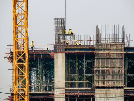 Construction man workers working on high building construction site. の写真素材
