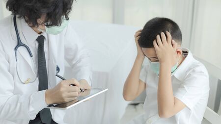 The doctor currently consulting with kid patient and wearing surgical mask for health care from Coronavirus (COVID-19). Health care and prevent from risk of Coronavirus (COVID-19) concept.の写真素材