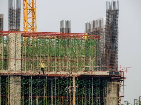 Construction man workers working on high building construction site. の写真素材