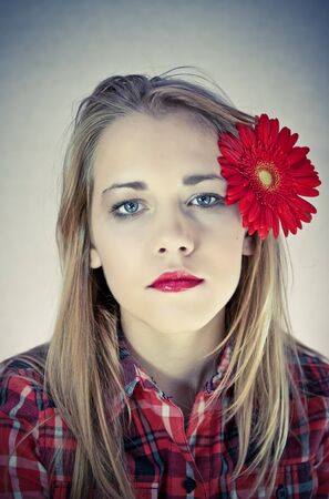 portrait of young beautiful woman with red flower in her hairの写真素材
