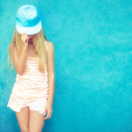 Portrait of a teenage girl in the cap with a blue wall の写真素材
