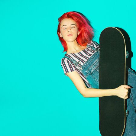 Pretty teenager girl with pink hair and skateboardの写真素材