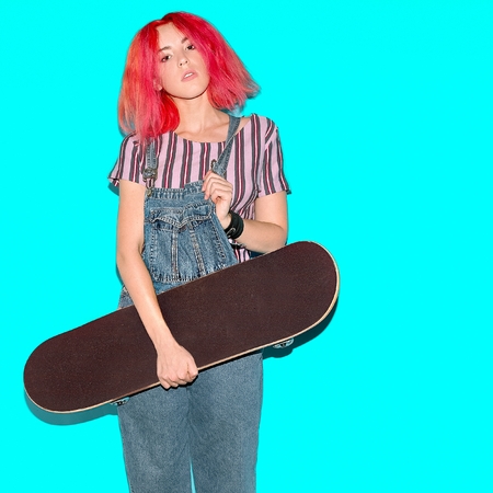 Pretty teenager girl with pink hair and skateboard Urban Style Jeans Fashionの写真素材