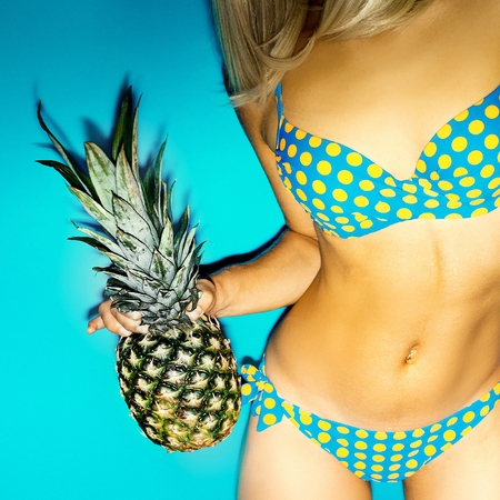 Girl with pineapple. Polka dot Swimsuit. Beach party style.の写真素材
