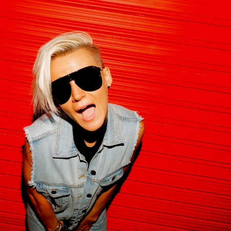 Funny blonde with short hair in stylish denim clothes and glasses on a red background