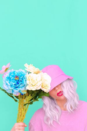 Hipster Lady with flowers in trendy bucket hat. Fresh summer vibes. Pastel colours loversの写真素材