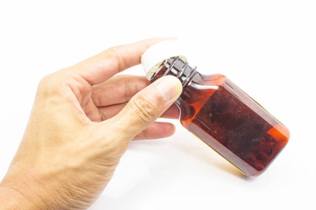 Prescription pill bottle spilling pills on hand isolated on white backgroundの写真素材