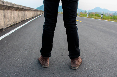 Low portrait of a man's legs and shoes from back on the road