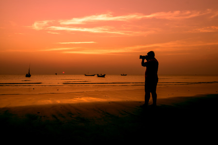 Evening sunset beach with a guy holding the camera.の写真素材