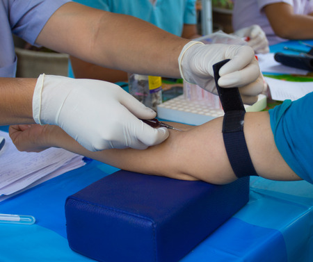 A doctor with syringe is taking blood for test.