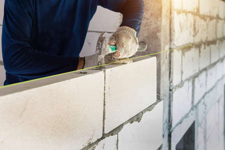 Real construction worker bricklaying the wall using tools.